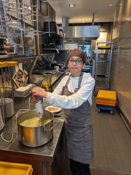 Junge kocht Suppe in einer Bäckereiküche