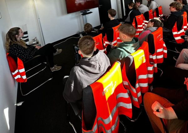 Boys'Day-Teilnehmer mit Warnwesten schauen eine Präsentation an