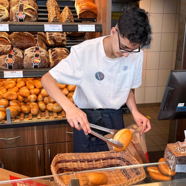 Boys'Day-Teilnehmer beim Einpacken von Brötchen in Brötchentüte