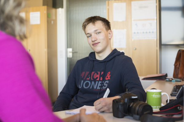 Junge sitzt am Schreibtisch und macht sich Notizen