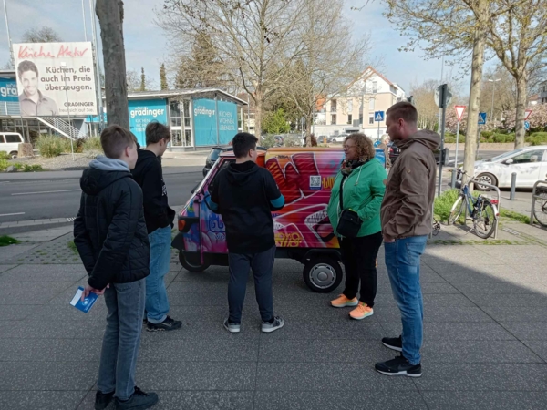 Boys'Day-Teilnehmer und Mitarbeitende vor einem besprühten kleinen Auto