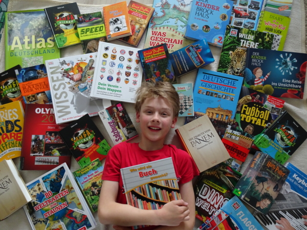 Junge mit vielen Büchern um sich herum