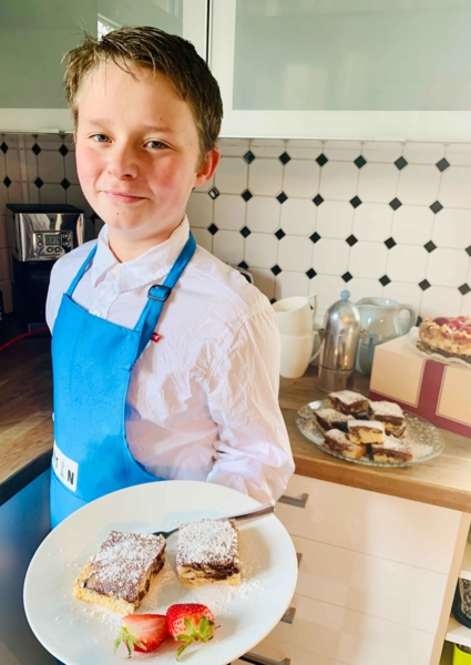 Junge präsentiert Kuchen und Erdbeeren