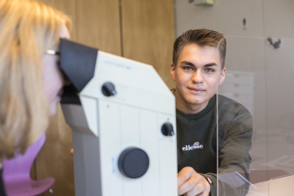 Junger Mann sitzt im Hintergrund eines Sehtestgeräts