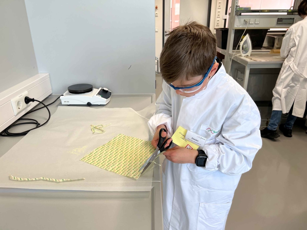 Junge in Laborkittel und Brillen schneidet Streifen