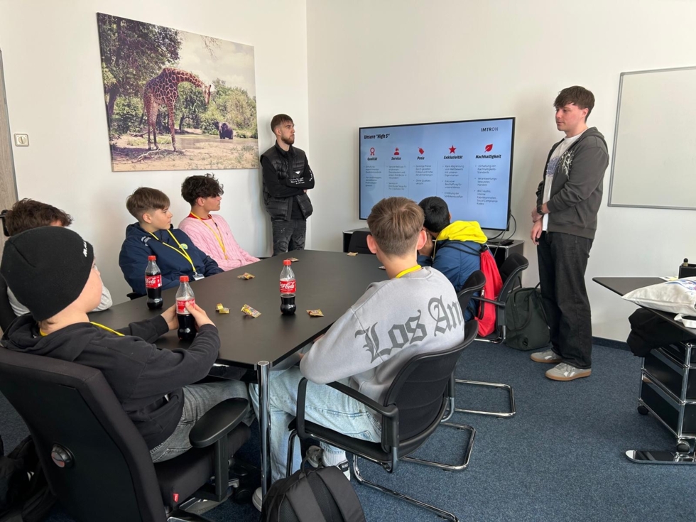 Boys'Day-Teilnehmer am Besprechungstisch schauen sich Präsentation an