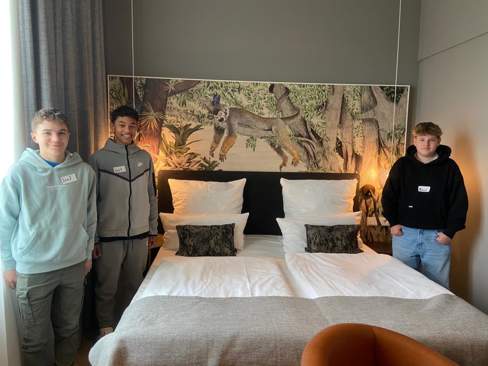 Boys'Day-Teilnehmer stehen nebeb gemachtem Hotelbett