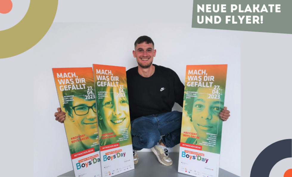 EIn junger Mann zeigt die neuen Boys'Day-Plakate 2023