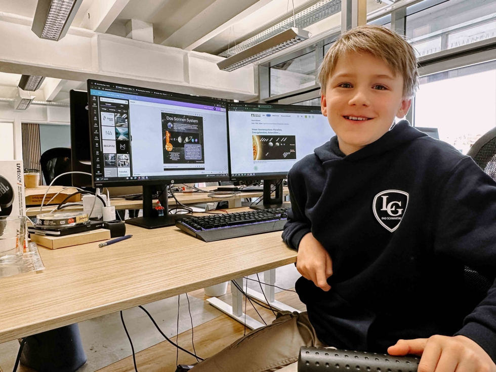 Junge am Schreibtisch vor Computern