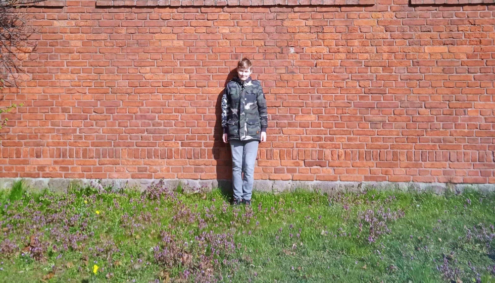 Junge vor einer Ziegelmauer