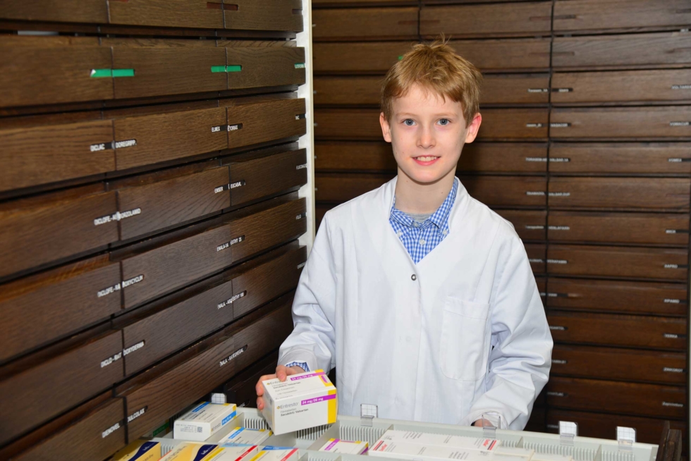 Boys'Day-Teilnehmer mit Medikamenten vor Apothekenschrank