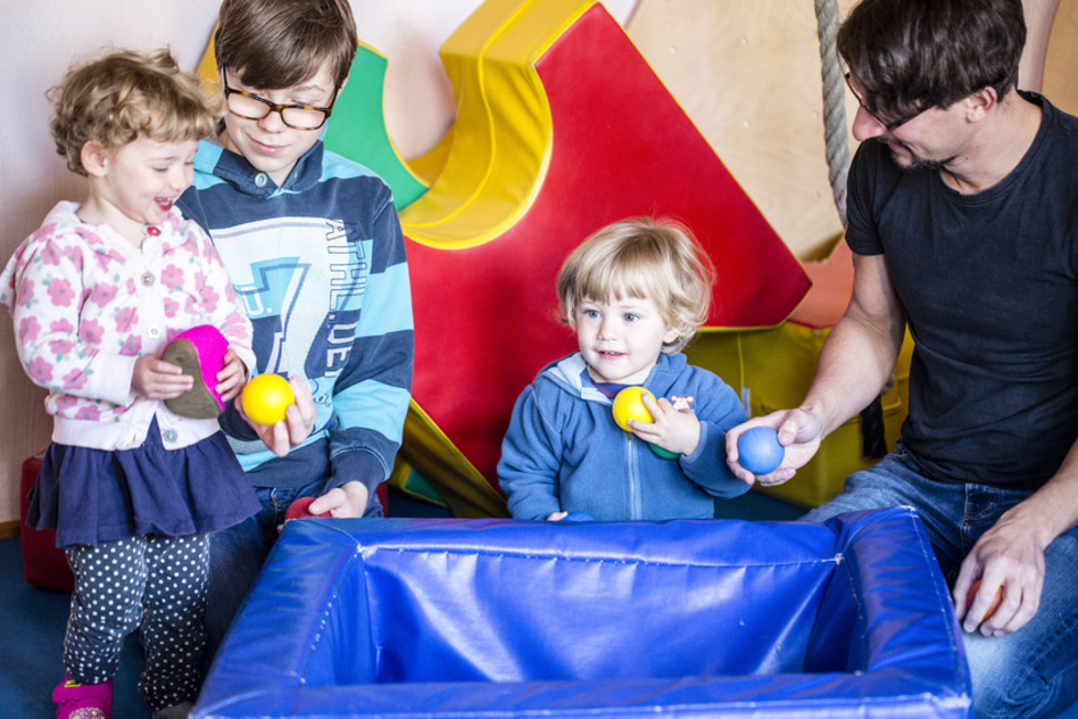 Junge und Mann spielen mit Kindern im Bällebad