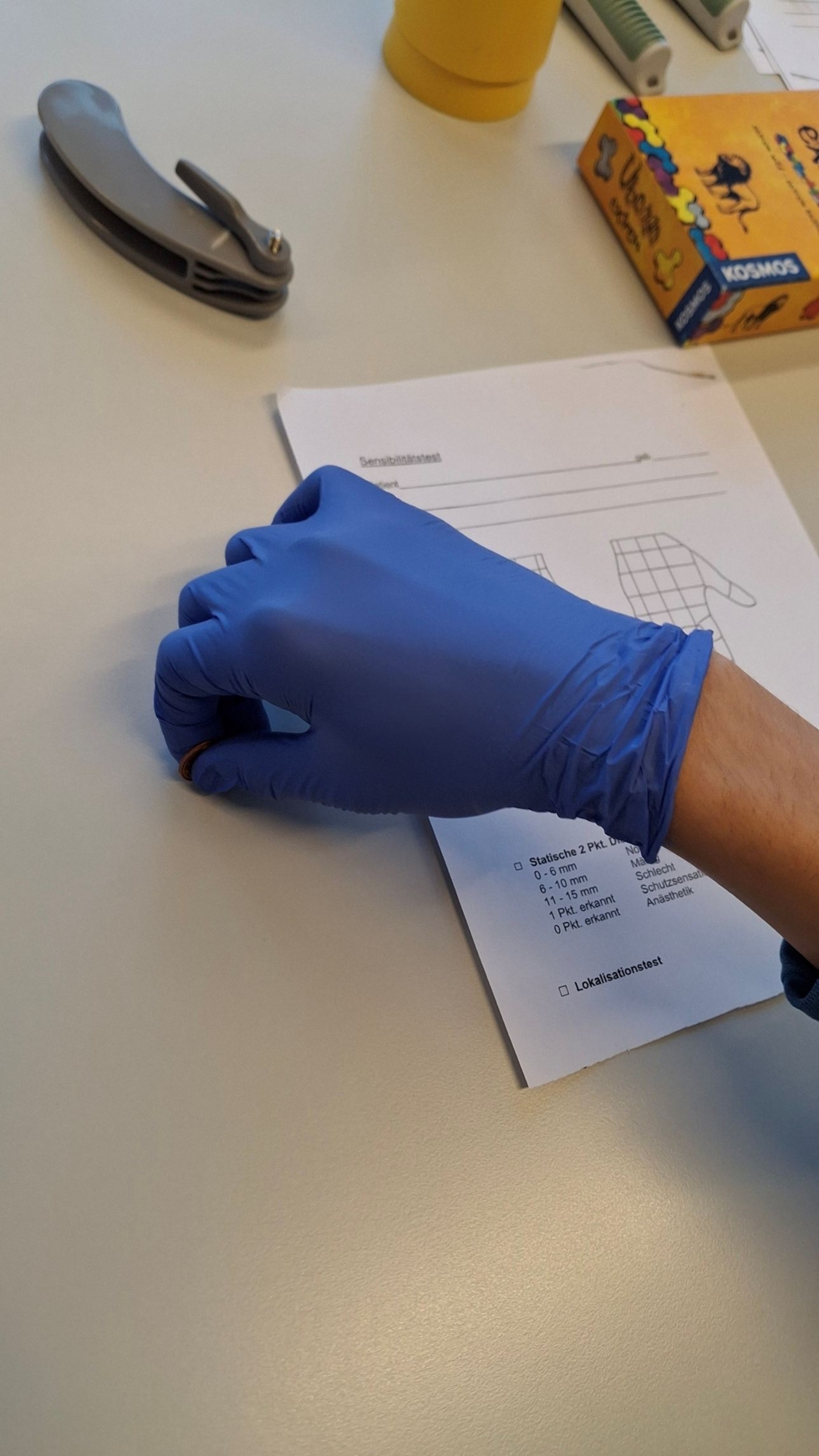 Hand mit Gummihandschuh liegt auf Tisch