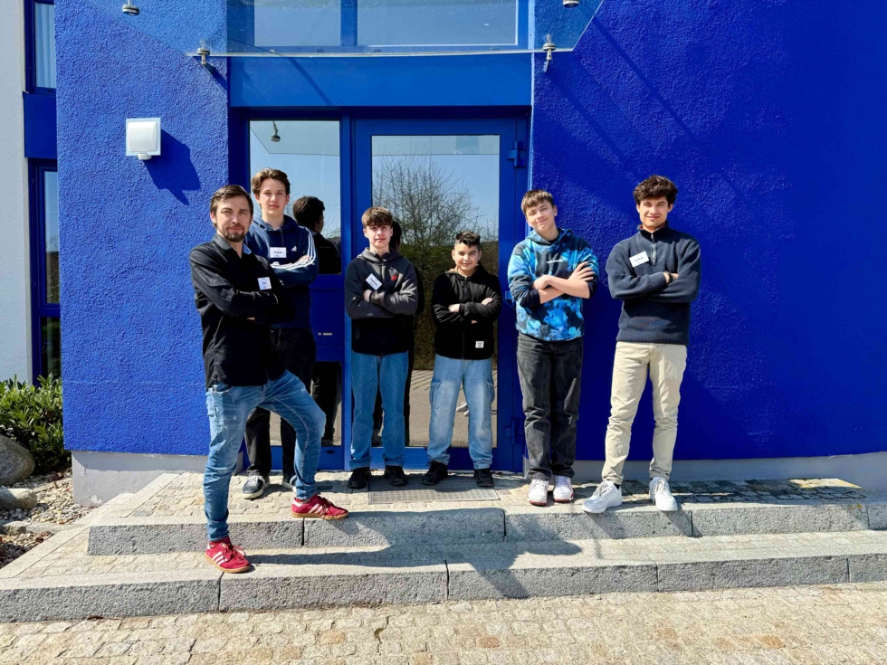 Boys'Day-Teilnehmer mit Mitarbeiter vor blauer Wand