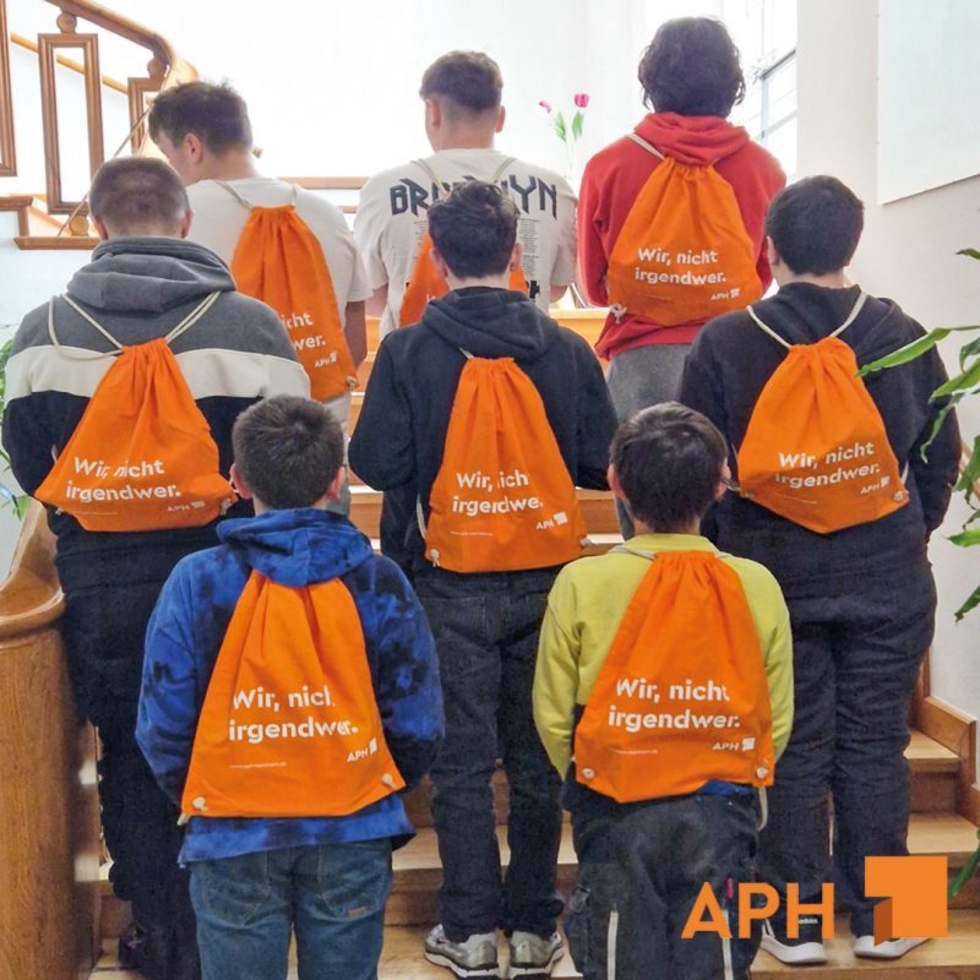 Gruppenbild mit Boys'Day-Teilnehmern mit Beuteln auf dem Rücken und der Aufschrift Wir, nicht irgendwer